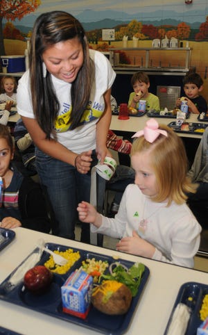 An Le gives Claire Stevens a green sticker for choosing white milk. Wofford and USC Upstate are conducting a study at Jesse Boyd Elementary to get students there to eat healthier.