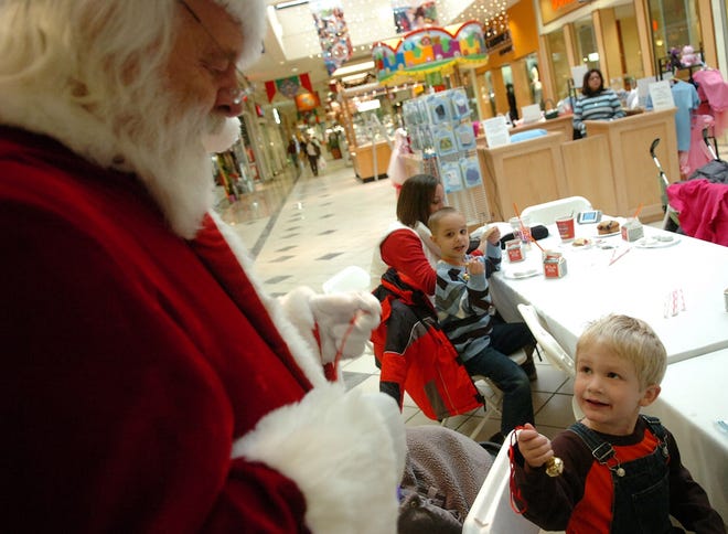 Santa hands 3-year-old Leeland Murphy of Brockton a sleigh bell during a breakfast with Santa event at the Westgate Mall in Brockton Wednesday morning.