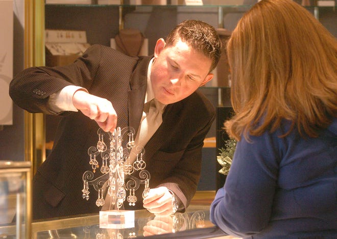 Daniel Zamsky, left, who works for Romm & Co. Jewelers in Brockton, shows Melissa Kripke of Taunton some Pandora earrings.