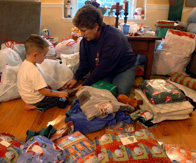 Sue Ranieri helps her grandson, Ethan Voss, 4, wrap presents yesterday for their upcoming annual Christmas party which will take place in Bellingham tomorrow.
