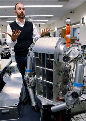 In this photo made Tuesday, Nov. 24, 2009, Ryan Calo, with the Stanford Center for Internet and Society at the Stanford Law School, stands next to a robot that is being built for medical applications at Stanford University's Artificial Intelligence Laboratory in Palo Alto, Calif.