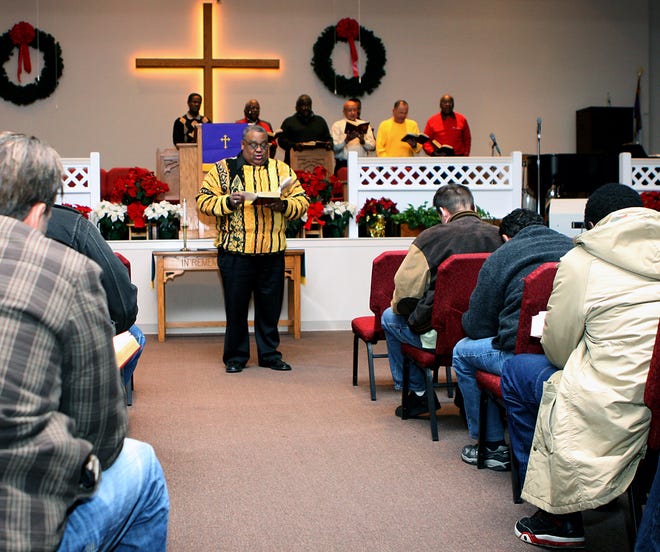 The Rev. J. Anthony Lloyd conducts a worship service before the Christmas dinner held at his church, the Greater Framingham Community Church, Friday in Framingham.