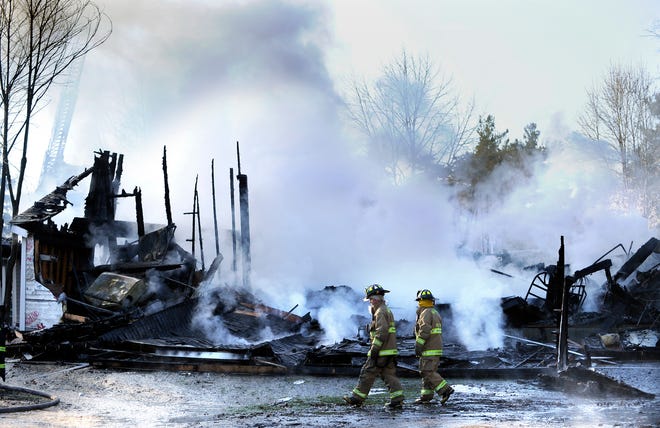 A pair of Waltham firefighters walk past the remains of the Fenn Center at the Gifford School in Weston. A four-alarm fire Wednesday morning destroyed the building.