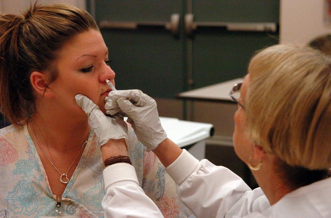 Julianna Klimaszewski, 23, of Canterbury, a patient care technician, gets the H1N1 nasal spray vaccine from Cindy Bessette, R.N. Wednesday, October 14, 2009 at the William W. Backus Hospital in Norwich. The spray is available to Backus health care workers.