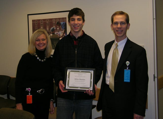 Miles Marden, center, a Belmont Hill School student, receives a Merit Award on behalf of his school community, for donation of DVD players to the children. Pictured with Marden aer Marilyn Gifford, MGH pediatric child life specialist, and Paul Bartush, director of Volunteer Services.