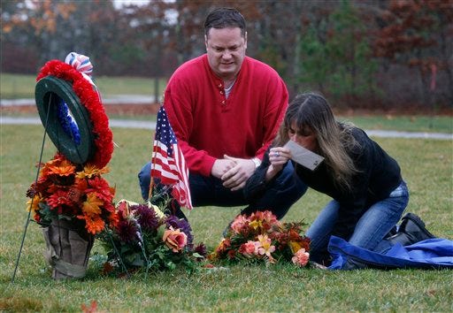 In this Wednesday, Nov. 25, 2009 photo Denise Anderson, right, of Mansfield, Mass., mother of fallen U.S. Army Iraq War veteran Corey Shea, kisses his photo as her brother Scott Anderson, center, looks on at the National Veterans Cemetery in Bourne, Mass. Shea was killed in action in Iraq in November of 2008. Anderson is determined not to lose her fight to be buried with her only son in a veterans cemetery.