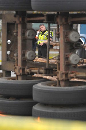 Garden City Police Officer is framed in the chasis of an overturned log truck trailor broke loose at the intersection of Alfred Street and US 80 in Garden City. Richard Burkhart/Savannah Morning News