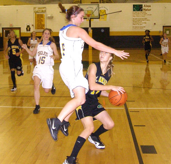 St. Amant’s Kaitlin McClure pump fakes Live Oak’s Brooke Morris into the air in the first half of the Lady Gators’ 39-32 semifinal victory at the Holiday Classic in the Gold Dome Monday night.