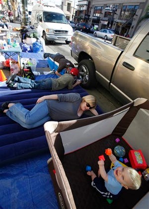 Amy Jahnke, and her seven-month-old toddler Parker, rest along the 2010 Rose Parade route where they spent the night Thursday in Pasadena, Calif. Today, millions of spectators from around the world will celebrate the New Year with the 121st Rose Parade. (AP Photo/Damian Dovarganes)