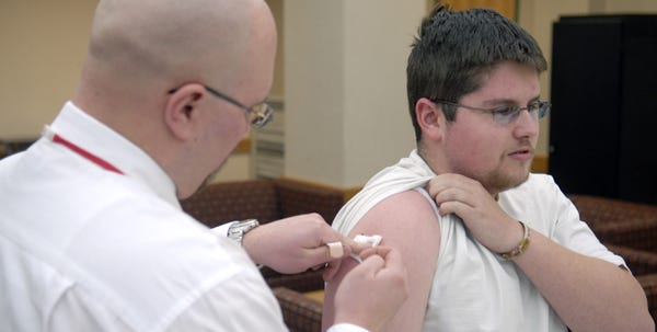 Patrick McDermott of Saylorsburg holds up his sleeve as Edward Szafran applies pressure to the injection site after administering the swine flu vaccine at the Monroe campus of Northampton Community College in Tannersville on Friday.