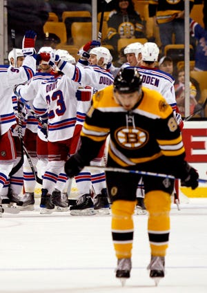 New York Rangers players surround goalie Henrik Lundqvist at the conclusion of their 3-1 win as Boston Bruins' Miroslav Satan, of Slovakia, leaves the ice at the end of an NHL hockey game Saturday, Jan. 9, 2010, in Boston. (AP Photo/Mary Schwalm)