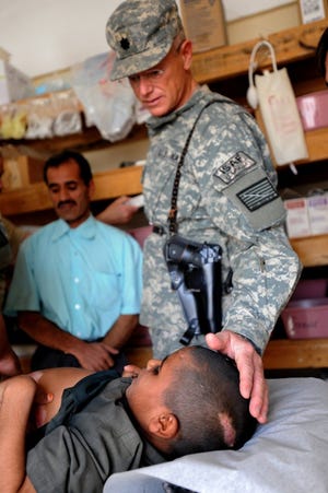 U.S. Air ForceNavy Cmdr. Mark Dobbertien, officer in charge of the forward surgical team assigned to Forward Operating Base in Farah, Afghanistan, comforts 8-year-old Ali Ahmad. Dobbertien, a surgeon normally based at Jacksonville Naval Hospital, says that in addition to handling U.S. casualties from the battlefield, his team also provides surgical help to local residents.
