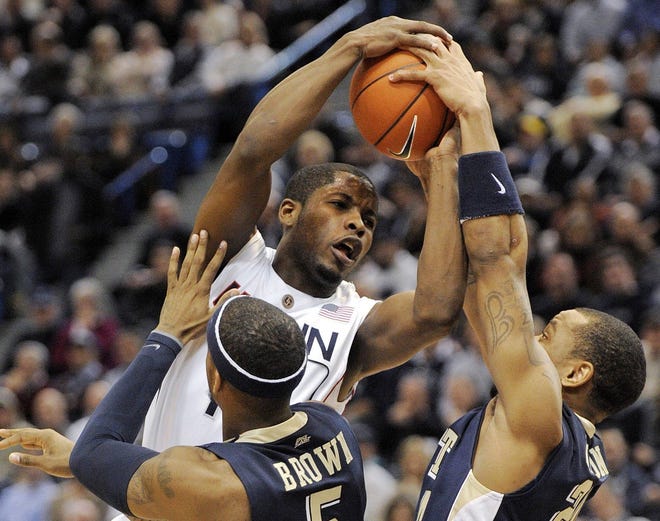 Connecticut's Jerome Dyson gets fouled while being guarded by Pittsburgh's Gilbert Brown and Jermaine Dixon during the first half of an NCAA college basketball game in Hartford, Conn., on Wednesday, Jan. 13, 2010.