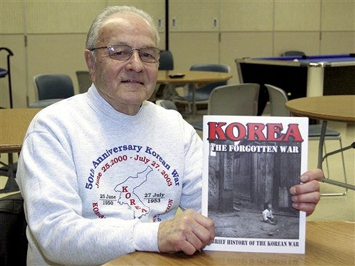 In this photo taken Dec. 31, 2009, Korean War veteran Hershall Lee poses with a copy of the book "Korea, The Forgotten War," in Danville, Ill. Members of the Illinois Korean Memorial Association put together the soft-cover 56-page book which contains numerous photographs, statistics, maps and stories about the war from June 1950 to July 1953. On the 60th anniversary of the start of the Korean War, the veterans are distributing the books, at no charge, to all junior highs, high schools and public libraries in the state. (AP Photo/Commercial-News, Deb Edwards)