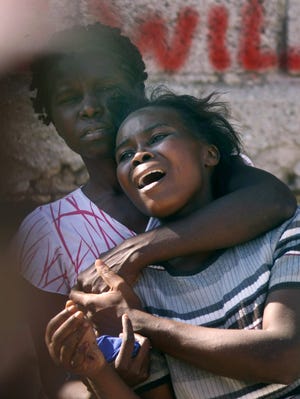 Elliane Garcon, right, cries as she watches the body of her husband, Rene Morancy, being removed from the aftermath of Tuesday's earthquake in Port-au-Prince, Friday, Jan. 15, 2010. (AP Photo/Gerald Herbert)