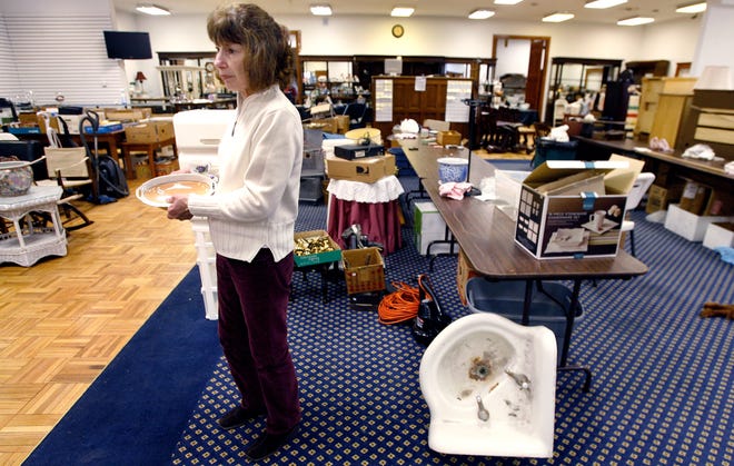 Patricia Doyle of Patricia Doyle Associates Auction Gallery, organizes items on the main sale floor for an estate sale.