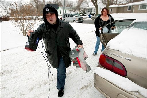 In this photo taken Jan. 12, 2010, Frank Small, of Xtreme Towing & Recovery in Decatur, Ill.,takes the child seat from the back seat while repossessing a vehicle on the west side of Decatur as his wife, Adelle, checks the vehicle identification number with their paperwork. (AP Photo/ Decatur Herald & Review, Stephen Haas)