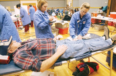 Dale Cummings of Canandaigua gets ready to donate blood as Jenna Rodas (left) and Kalyn Korber of the Red Cross get redy to draw blood.