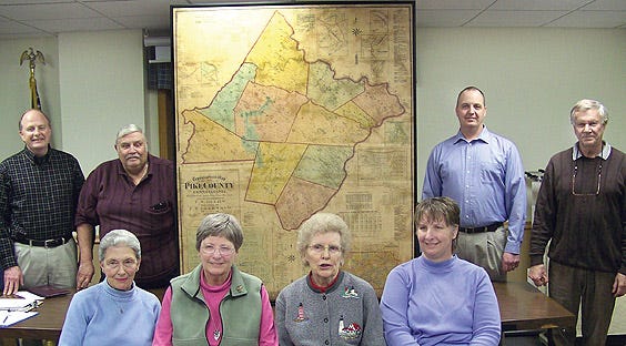 Back row, from left, Palmyra (P) Township Supervisors Eric Ehrhardt, Thomas Simons, Ken Coutts, and WHS member Richard Briden and front row, WHS members, Ann Weidenman, Inge Beidleman, Jan Coutts and Debi Stewart display the restored 1872 Beers map of Pike County. The map is now on display at the Palmyra (P) Township Building off of Gumbletown Road, on Buehler Lane, Paupack.