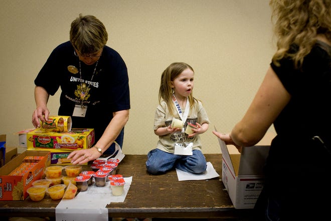 Lauren Thonn, 4, of Moline, center, along with her grandmother, Pam Thonn, left, of Moline, help pack single servings of pudding into care packages Saturday for Illinois troops serving in Afghanistan and Iraq during the Illinois Elks Association Meeting at the Crowne Plaza in Springfield.