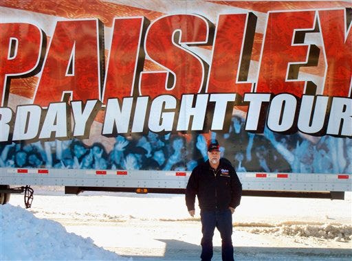 In this handout photo taken Jan. 12, 2010, Paul Dunham, of Saybrook, Ill., poses in Carroll, Iowa, by his rig promoting country singer Brad Paisley's "American Saturday Night Tour." Dunham has been behind the wheel of assorted Paisley tours for 4 1/2 years now, and he wouldn't have it any other way.