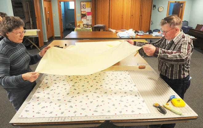 Marian Hayes of Forreston and Glenn Schneiderman of Baileyville move a measured backing to a quilt Monday at First United Methodist Church in Forreston.