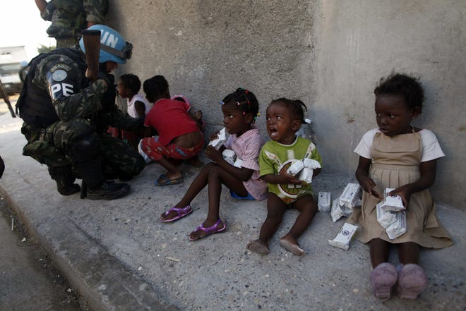 A girl cries after receiving food in an improvised distribution center organized by the United Nations as a U.N. peacekeeper from Brazil kneels to talk to children at the Cite Soleil neighborhood yesterday in Port-au-Prince.