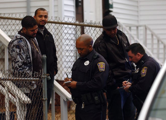 Brockton police talk to neighbors as they investigate the scene where two men were shot in a drive-by shooting as they were walking along Hancock Street in Brockton around 3 p.m. Sunday.