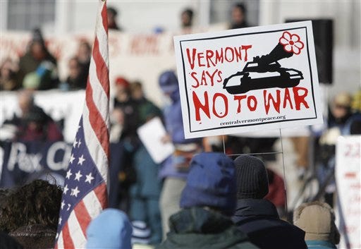 In this Feb. 11, 2006, file photo, a protester holds a sign during a rally at the Statehouse in Montpelier, Vt. Vermont, a bastion of ex-hippies and Ben & Jerry liberals, has another distinction seemingly at odds with its peace-loving, tie-dyed politics: It has suffered more deaths per capita in the Iraq war than any other state. (AP Photo/Toby Talbot, file)