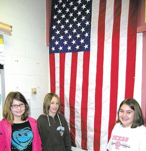 Hooverville Elementary School fifth-graders Zowie Sanders, left, Chelsea Cover and Anna Kensinger stand at the American flag that flew over Camp Leatherneck in Afghanistan on Dec. 25, 2009.