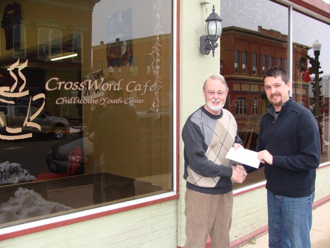 Sharing the funds: Brent Ressler, right, hands John Heffron a $500 check to help with operating expenses of CrossWord Café. Ressler, executive director of Small World Connections, donated the money to show the organization’s commitment to helping local groups, as well as international ones, through a new resale shop endeavor.