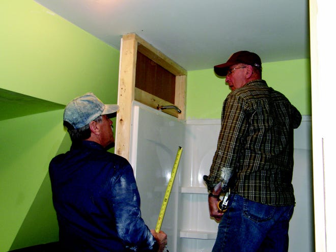Volunteers Paul Spofford and Roy Van Slyke work inside a bathroom at the Habitat for Humanity House in Ilion Wednesday.