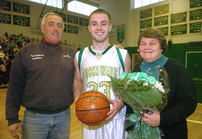 Kristian LaPointe, center, with his parents Glenn, left, and Diane, right, after he received a basketball from Abington High School and gave his mother a bouquet of flowers. The game was stopped after he scored his 1,000 career point.