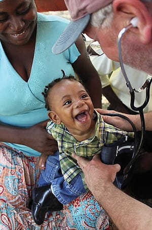 Dr. Steve Edmondson gets a big smile from a young Haitian as he checks his vitals. Edmondson spent 11 days in the shell-shocked nation, establishing a makeshift hospital and treating hundreds of injured and sick Haitians.