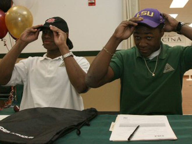 Dionte Ponder, left, who signed with Troy and Kadron Boone, right, who signed with LSU, try on their hats during their signing ceremony at Trinity Catholic High School in Ocala, Fla. on Wednesday, Feb. 3, 2010.