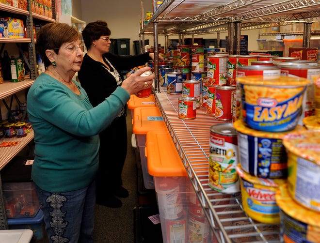 Ann Lambert, left, and Karen Regan check dates on canned goods yesterday at Project Just Because Food Pantry in Hopkinton.