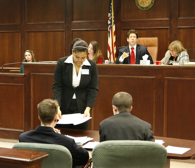 Michaela Jackson-Smith of Lakeridge shows documents to defence attorneys Bill Welch left and Matt Reed from Hoover High School during a hypothetical case Alex Leslie vs Erchwon Local School District. Judging the 2010 Ohio High School Mock Trial Competition are Melissa Day, Frank Forchione, and Wendy Rockenfelder.