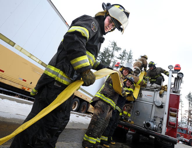 Recruits at the Massachusetts Firefighting Academy in Stow put out blazes in the Burn Building.
Plainville recruit Dan Moore helps roll up a firehose after a drill.