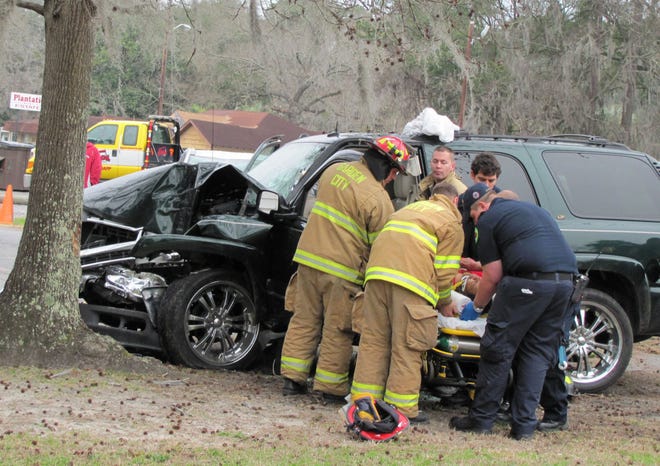 Garden City firefighters extricate the driver of a Chevrolet Tahoe that crashed into a tree in front of Little People Palace on Ogeechee Road Tuesday afternoon. Police said her injuries were not life-threatening and charges were pending. Michael Atkins/Savannah Morning News