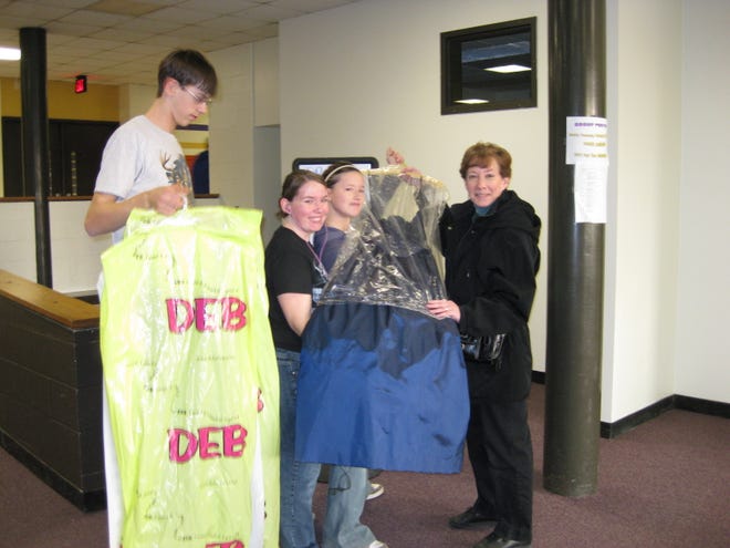 Canton High School CORE students accept a prom dress donation from District 66 faculty member Becky Grace (at right). The students are collecting dresses and offering them free to promgoers. From left are students Cody Barclay, Debra Wartenbe, and Bree Tangman. As of Monday, 70 brand new dresses were donated with more donations arriving.