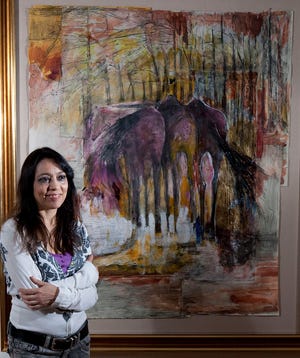 Artist Vivian Jendzio of Gainesville poses next to her painting of horses, "Standing There Dreaming," a mixed-media piece that includes graphite, ink, charcoal and acrylic paint on paper, at the Icehouse Gallery in McIntosh on Tuesday.