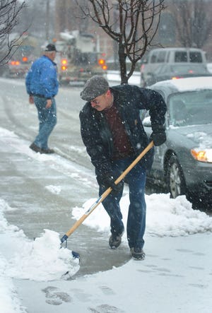 Joe Dever, a custodian at the Weymouth Landing post office, clears the front walkway of snow during Tuesday’s storm.