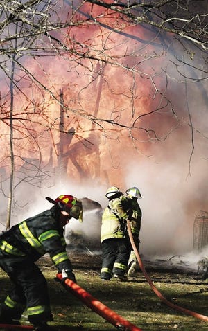 MIKE VALERI/The Standard-Times
Acushnet firefighters begin extinguishing a fire in a storage barn behind a home along Middle Road in Acushnet Friday.