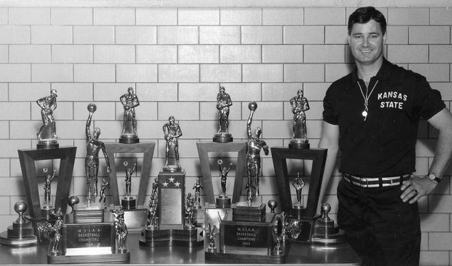 Former Kansas State coach Tex Winter posed with seven of the eventual eight Big Eight championship trophies he would win during his 15 seasons as the Wildcats head coach from 1953-68.