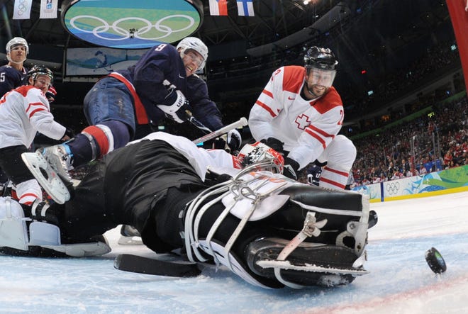 USA's Zach Parise (9) scores past Switzerland's goalie Jonas Hiller and Switzerland's Thierry Paterlini (23) in the third period of a men's quarterfinal round ice hockey game at the Vancouver 2010 Olympics in Vancouver, British Columbia, Wednesday, Feb. 24, 2010. The USA won 2-0. (AP Photo/Bruce Bennett, Pool)