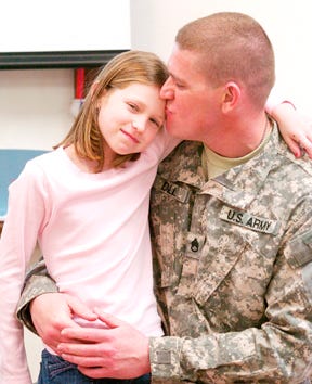 Staff Sgt. Anthony Dill kisses his daughter, Lily Dill, 9, Friday before leaving her class to speak to his son's class at Ivalee Elementary School as part of Career Day. Dill surprised his children Monday at school when he returned home from deployment in Iraq.