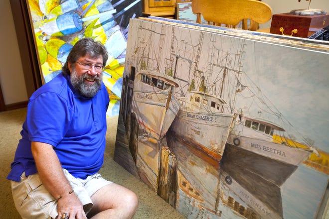 Artist Robert Stebleton poses with some of his acrylic maritime paintings in his Ocala home Wednesday. Stebleton is planning to open a new art gallery in downtown Ocala next month.