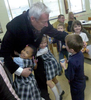 Reverend Msgr. Lew Gaetano recieves hugs from Hannah Smith and Anya Hester as he talks to Blake Shimko during a visit to the Our Lady of Peace after school program. The program outgrew its original location at St. Paul's of Canton, so it was moved to OLOP school.