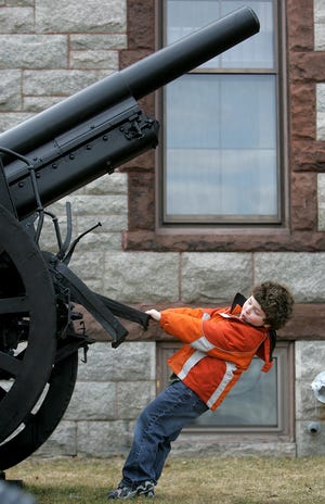 Paul Mahoney, 7, of Milford tries to budge an old artillery piece by pulling on the large structure with all his might while waiting for Memorial Hall in Milford to open with friends before the premiere of Lego Builders Club Monday afternoon. The club is open to children in Milford for grades kindergarten-second grade.