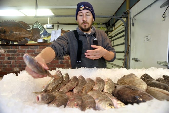 Tommy Bridges of Motts Channel Fresh Seafood store in Wrightsville Beach arranges rows of fish for sales.